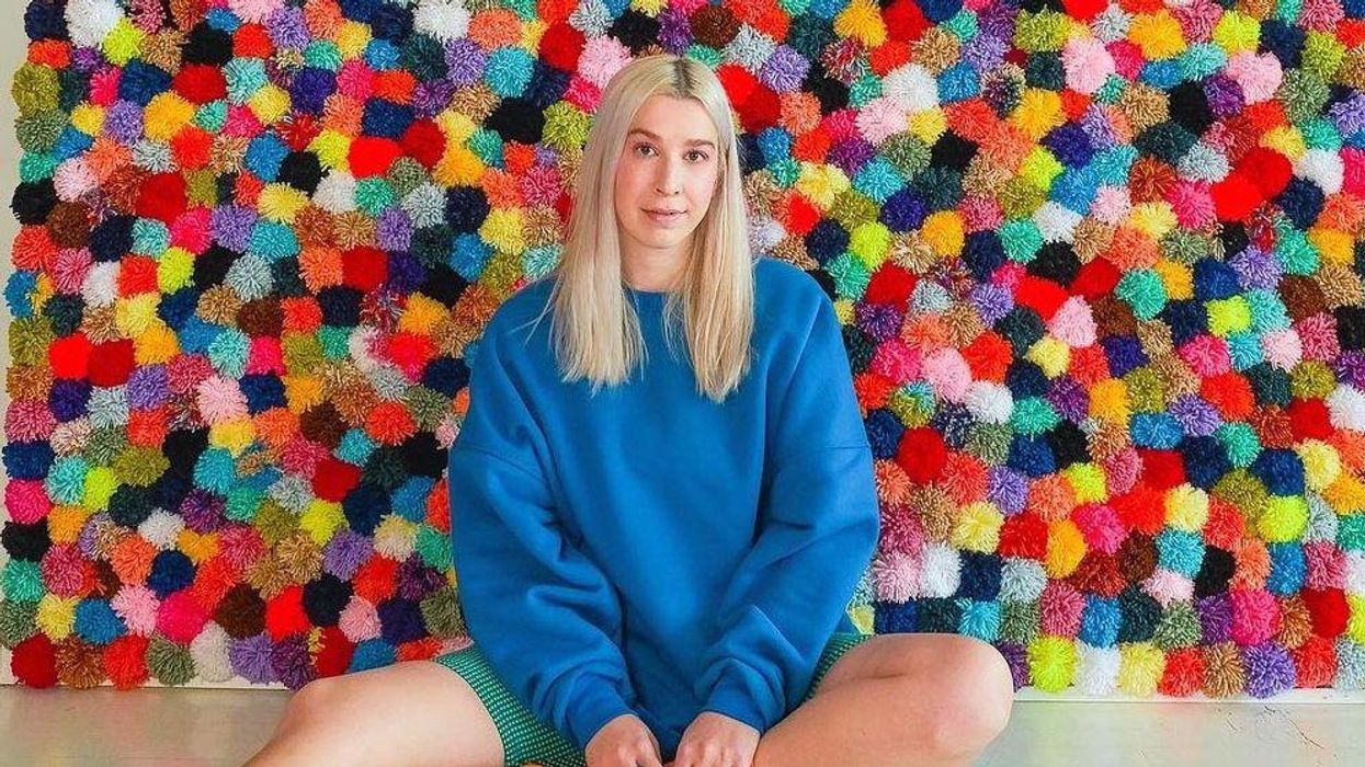 Marianne Plaisance devant son mur de pompons.