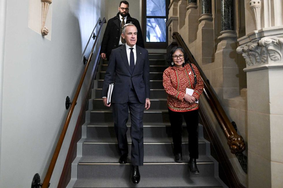 Mark Carney and Lori Idlout descend a flight of stairs side by side.