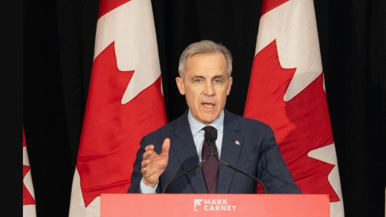 Mark Carney devant des drapeaux du Canada.
