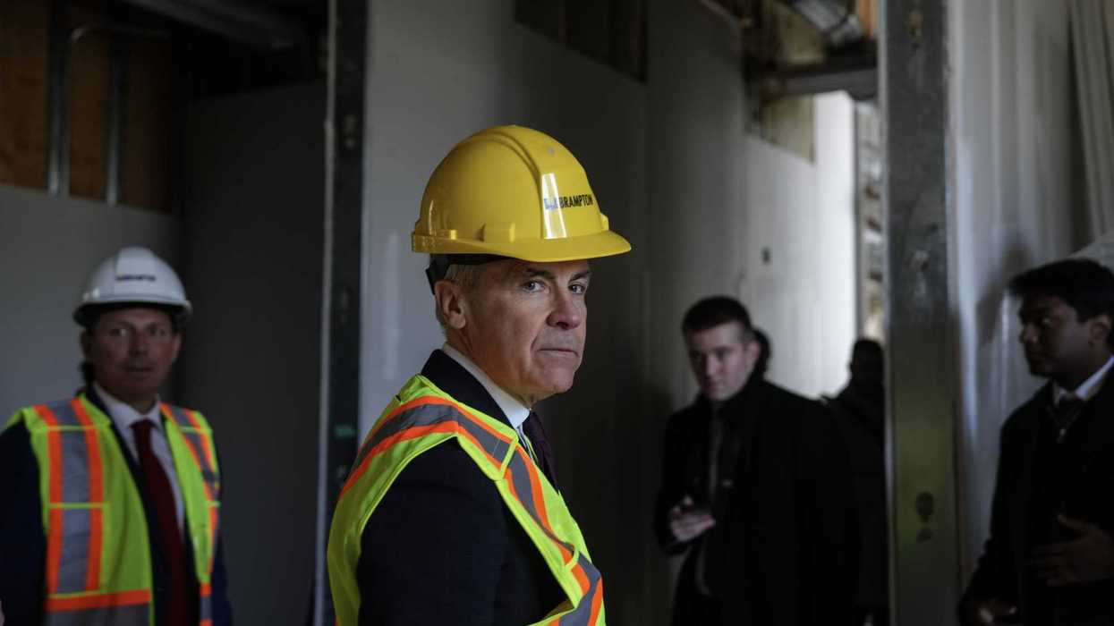 Mark Carney in a yellow construction hat and reflective safety vest.