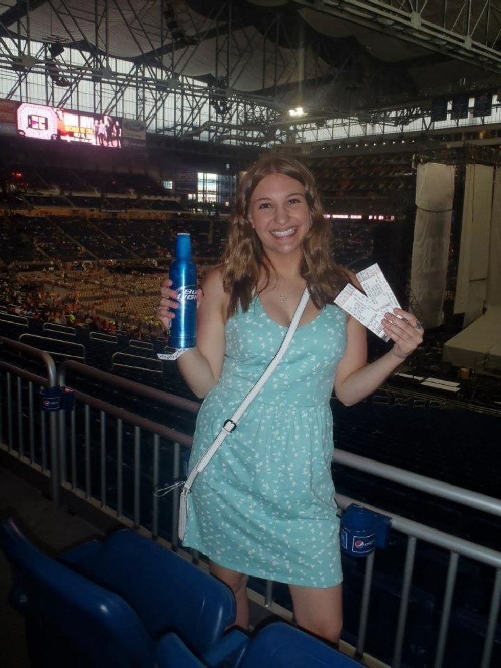 Megan holding tickets at Taylor Swift's Red tour concert in Detroit, Michigan.