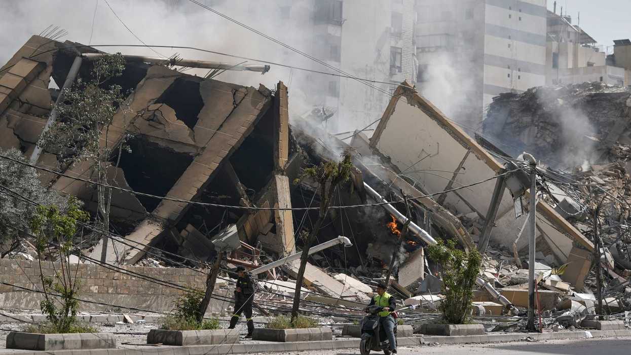 Men pass a building destroyed in an Israeli airstrike in Beirut.