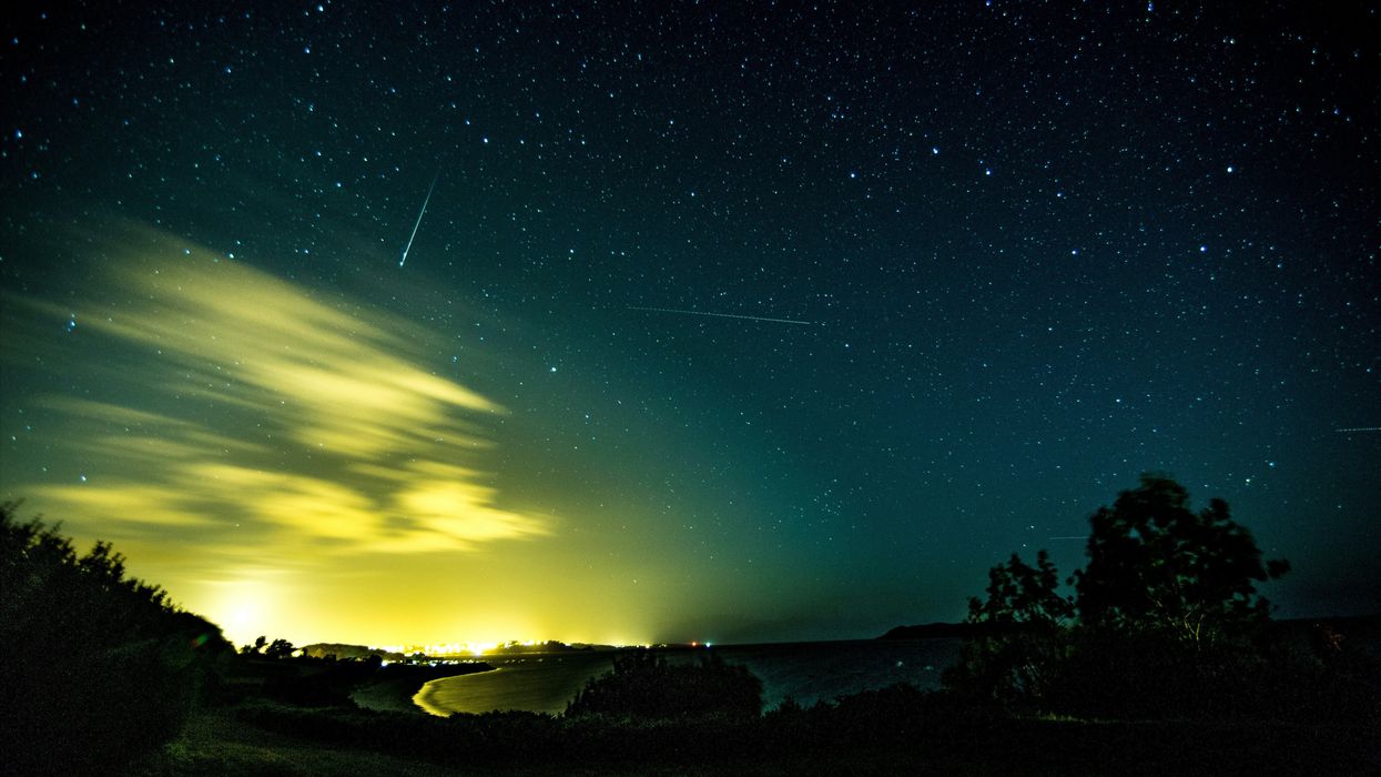 meteors and stars in a partly cloudy night sky