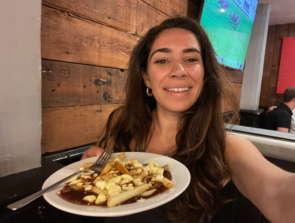 Mira holding a poutine in a restaurant in London.