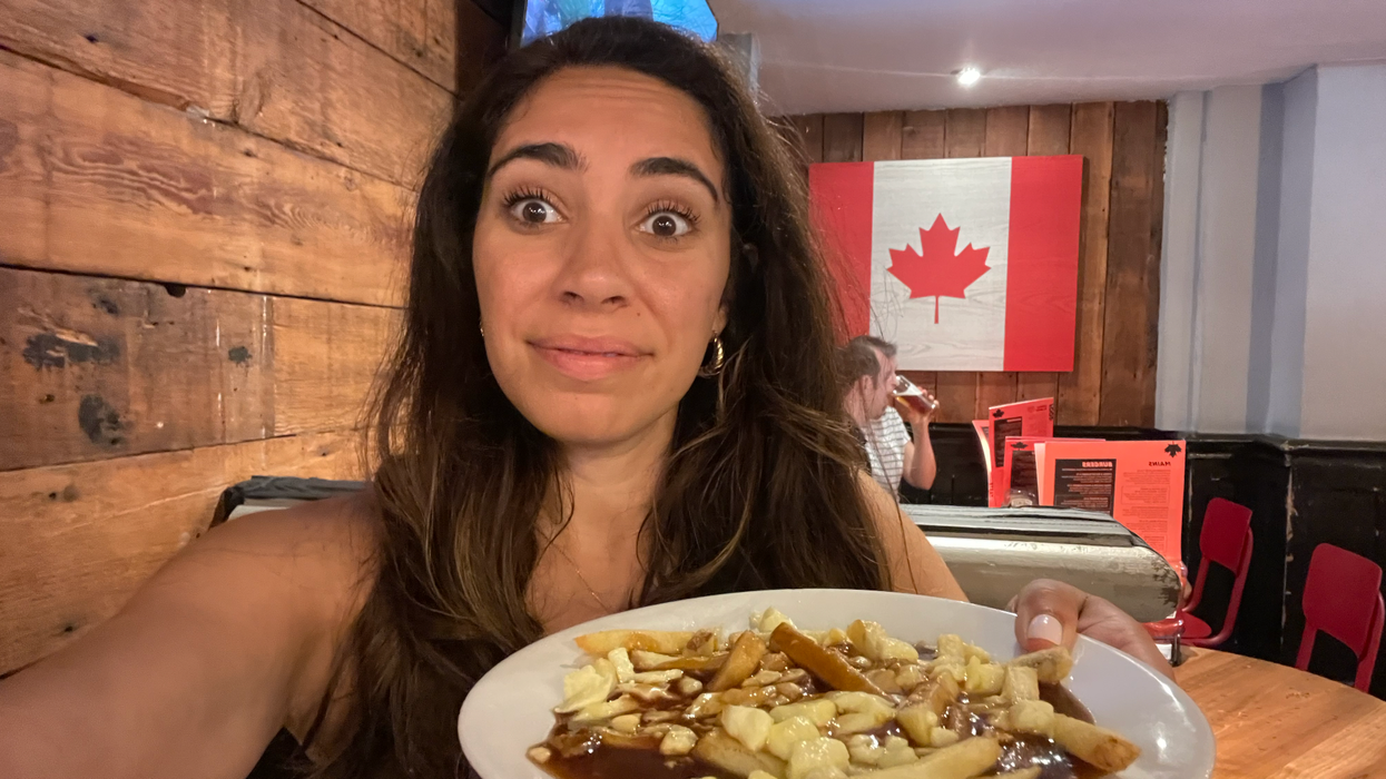 Mira holding a poutine in a restaurant in London.