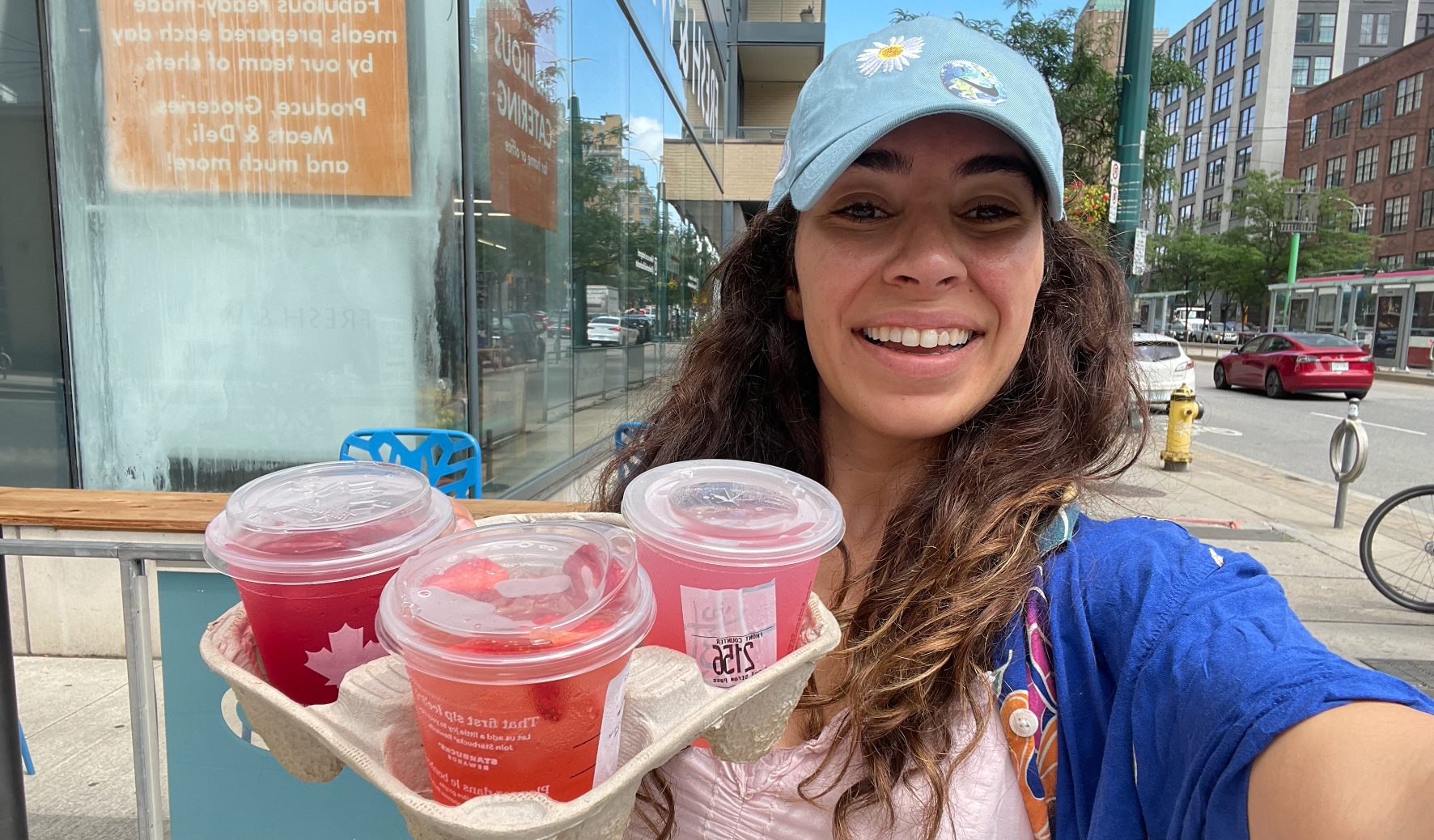 Mira holding three strawberry fruity drinks.