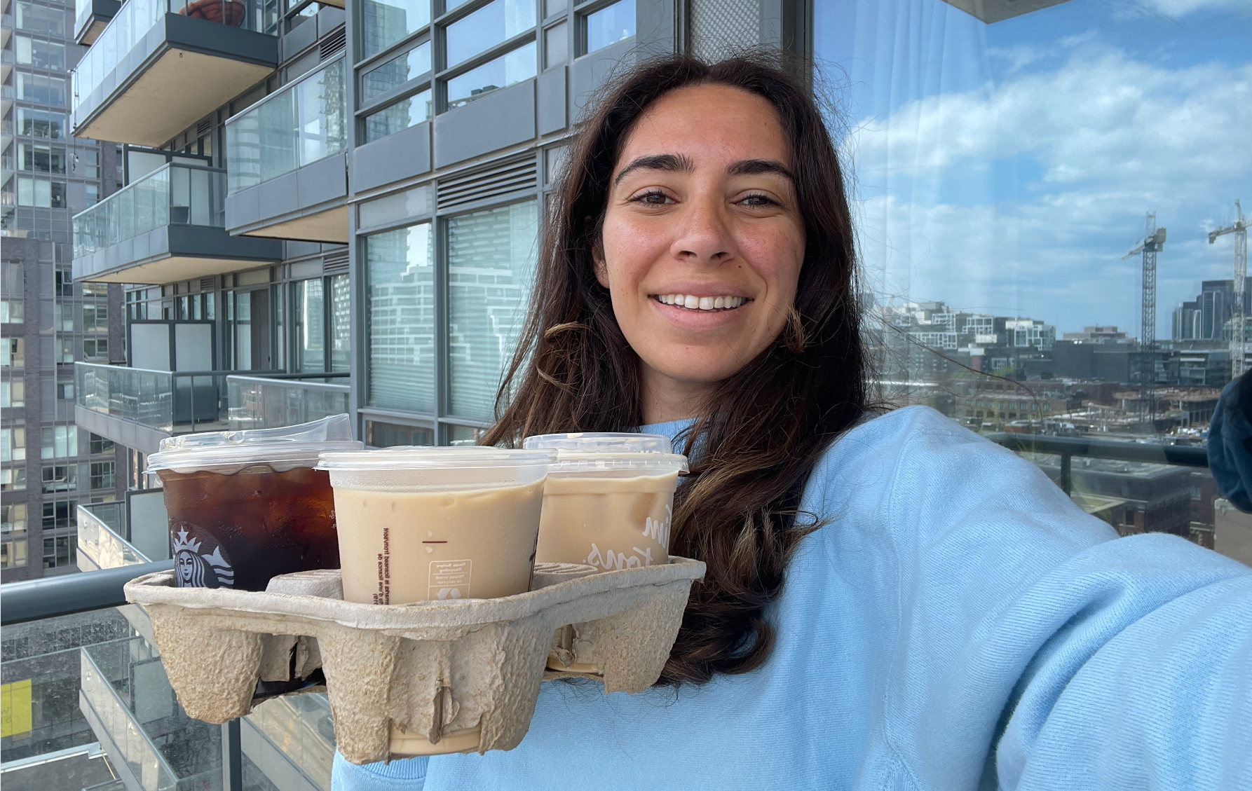 Mira Nabulsi holding three iced coffees from fast food restaurants in Canada.