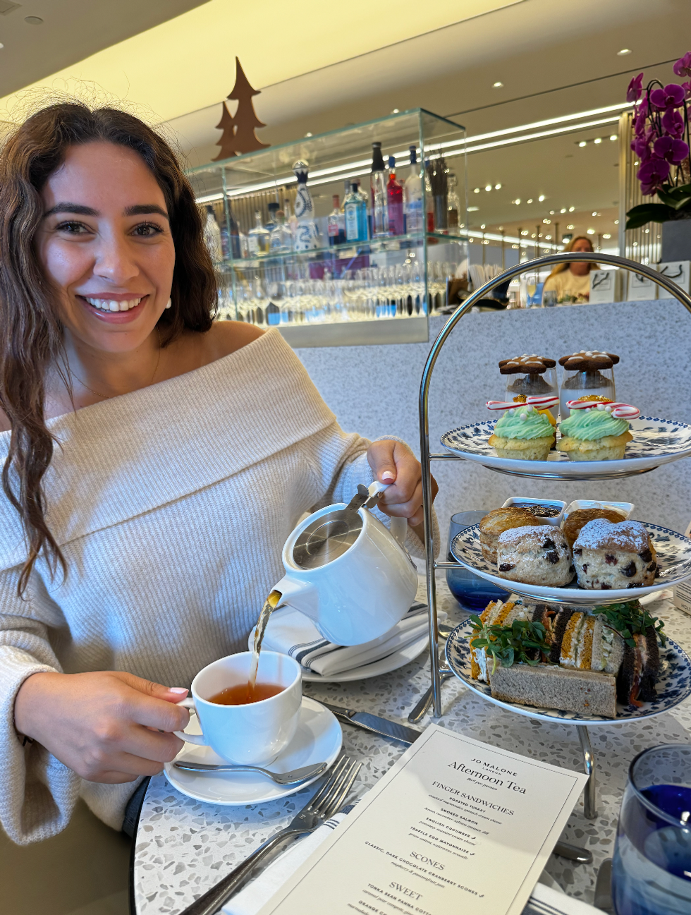 Mira pouring her tea with her afternoon tea tower at Holts Cafe in Toronto.