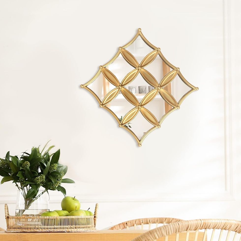 Miroir d\u00e9coratif carr\u00e9 et dor\u00e9, accroch\u00e9 sur un mur.