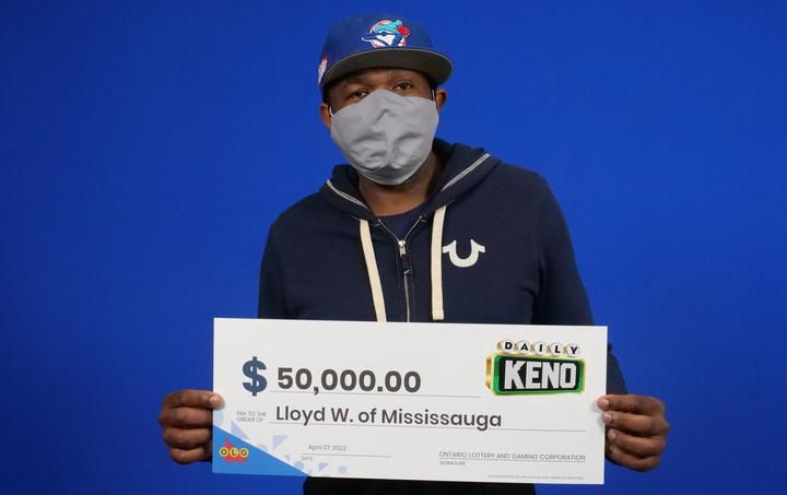 Mississauga resident Lloyd Wright holding up his cheque for $50,000.