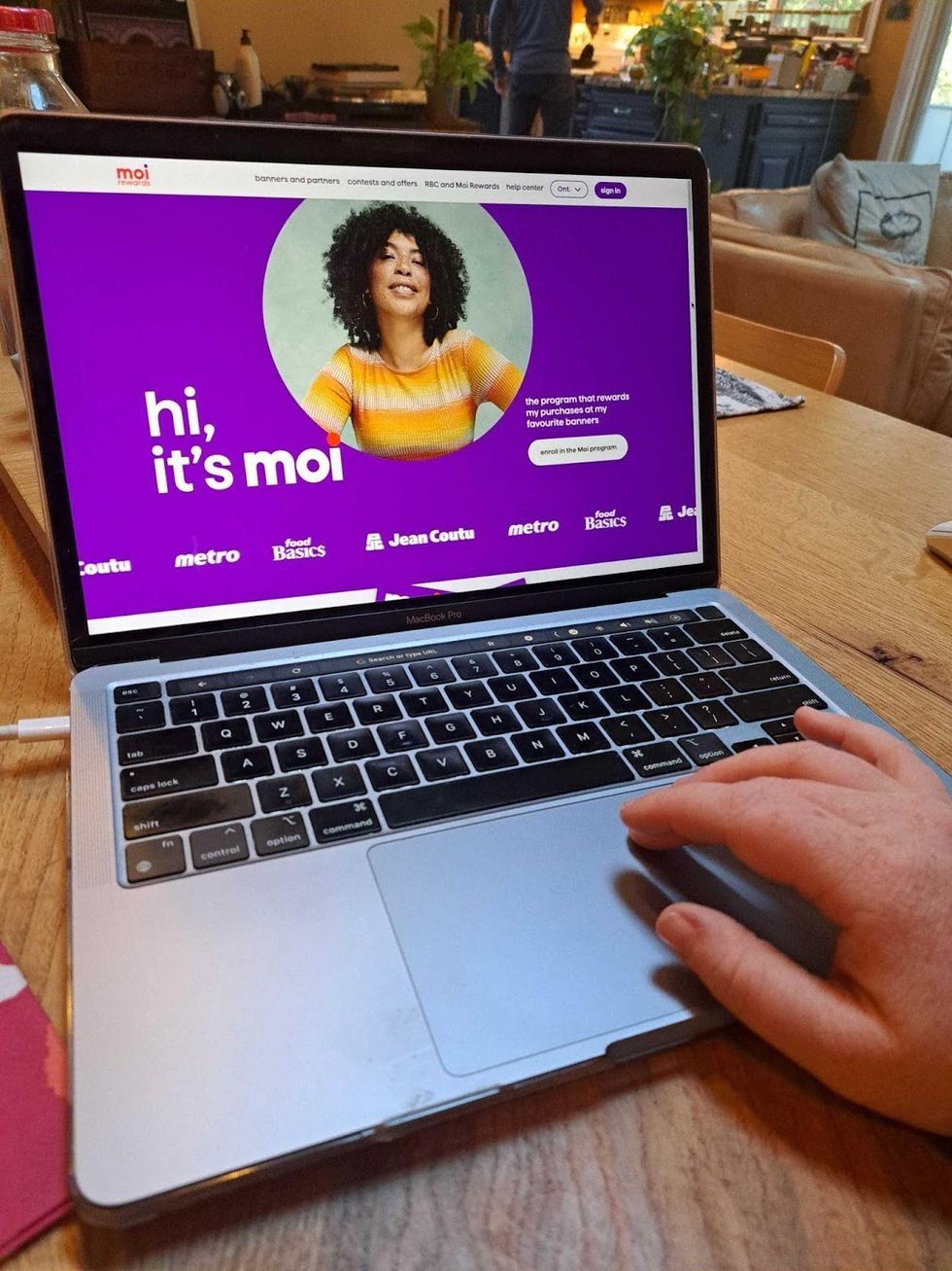 Moi Rewards website shown on laptop with a hand on the mousepad.