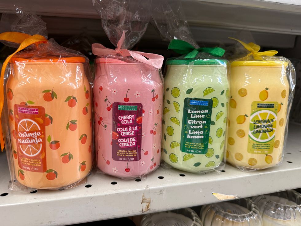 Multi-coloured glass jars on a store shelf that say scented candles on them in various scents.