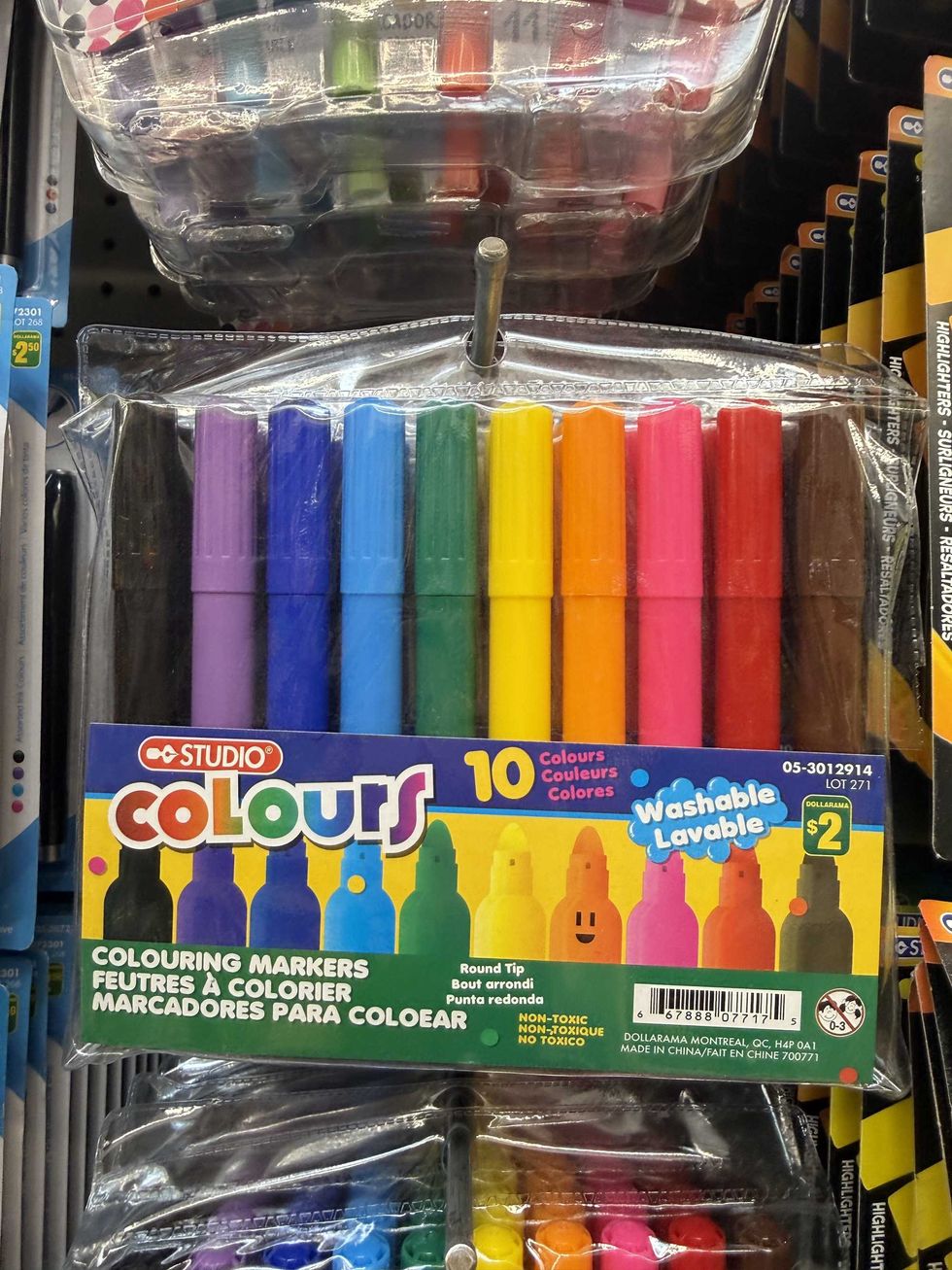 Multi-coloured markers in a clear bag hanging on a store shelf with writing that says Studio Colouring Markers on the front.