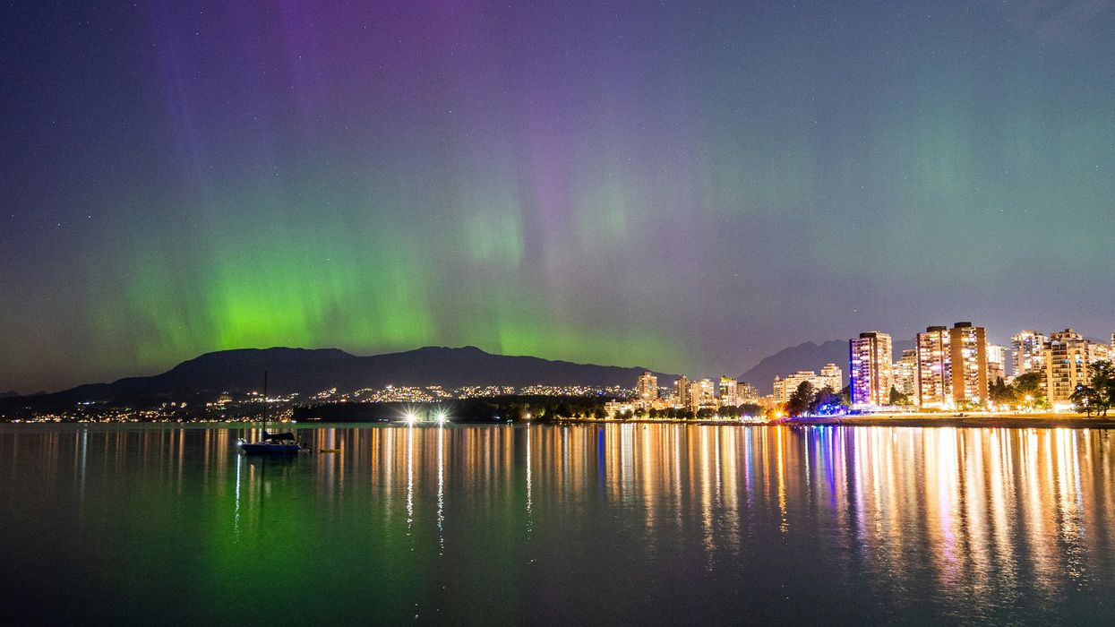 northern lights in the sky above mountains and buildings in vancouver