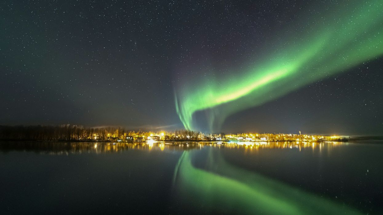 northern lights over houses along a lake in saskatchewan