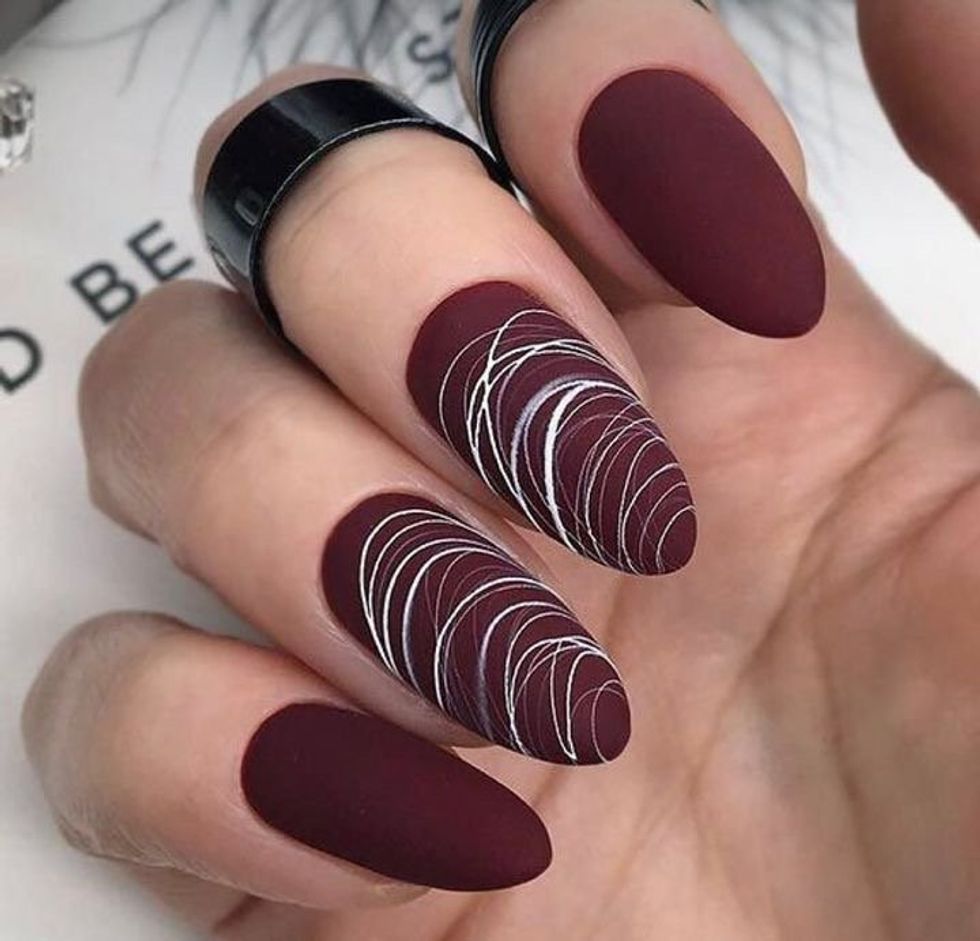 Ongles de couloir bourgogne avec de fines lignes blanches entrecrois\u00e9es.