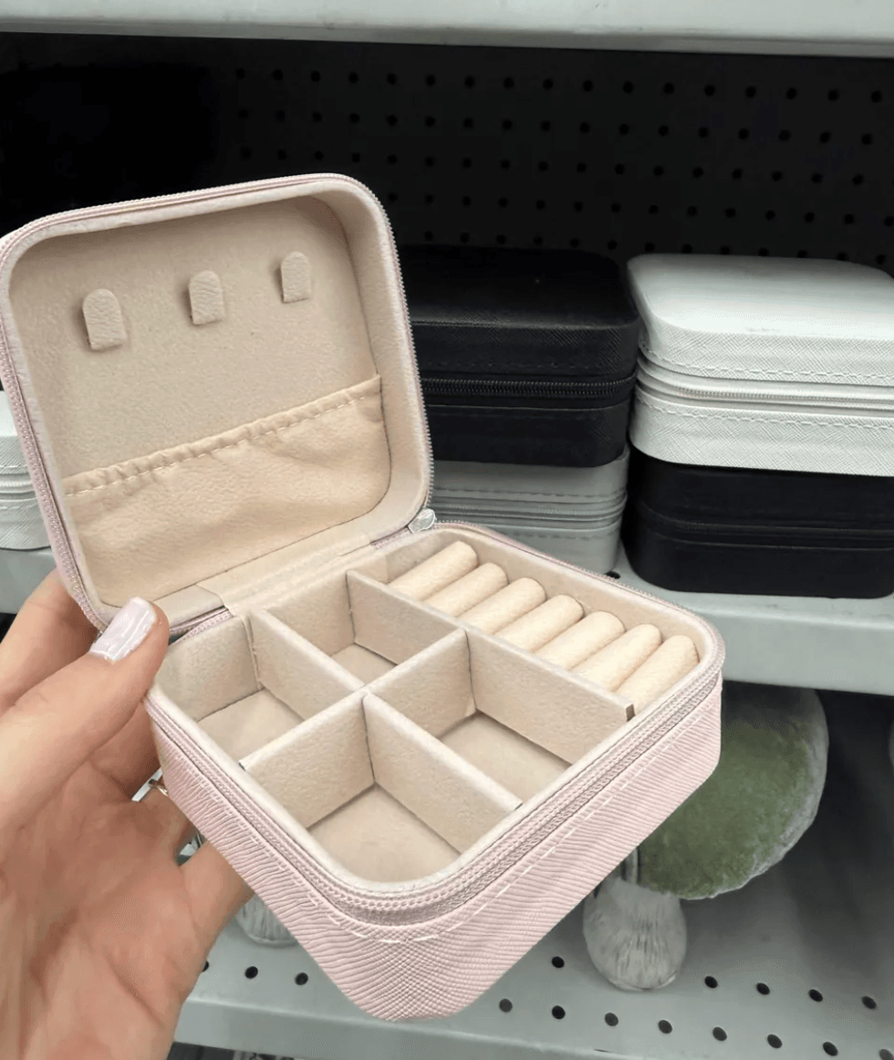 Open pink jewelry organizer with ring slots and compartments.