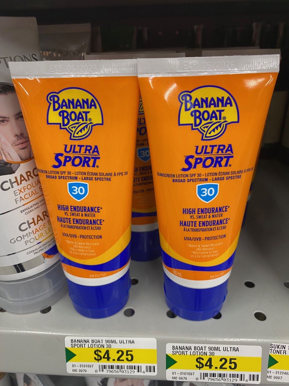 Orange and blue coloured tubes of sunscreen on a store shelf.
