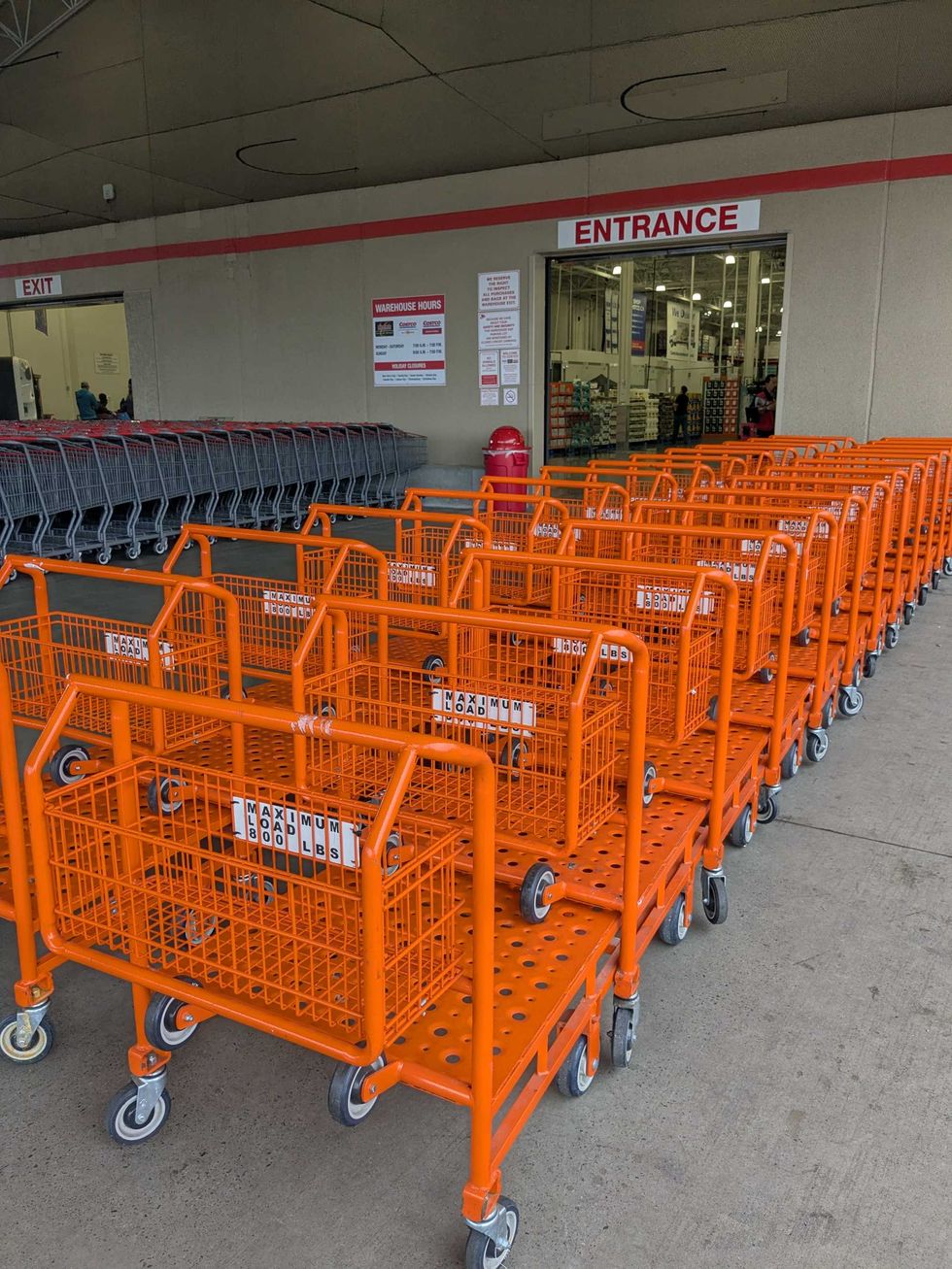 Orange flatbed carts lined up outside a store entrance.