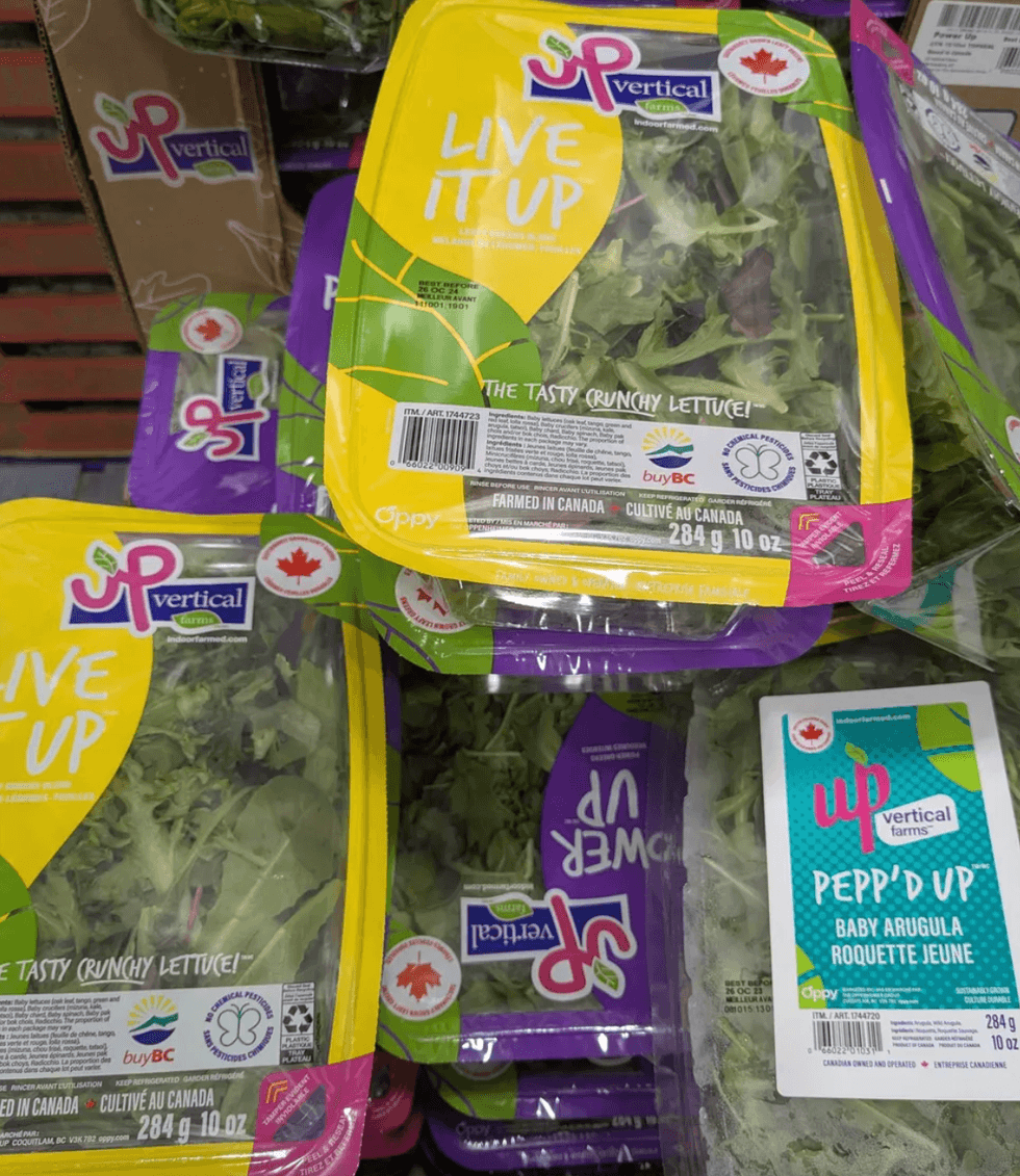 Packages of UP vertical farm lettuce and arugula with colorful branding.