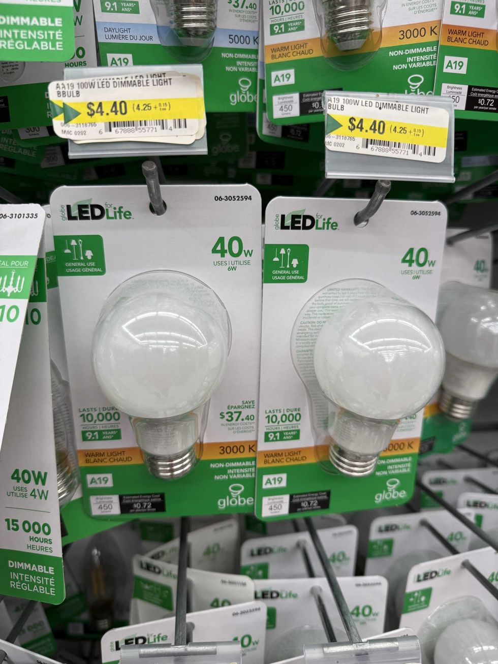 Packs of light bulbs hanging on a store shelf.