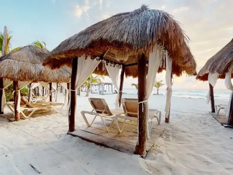 Palapas avec rideaux sur la plage de sable blanc du Flamingo Cancun Resort au Mexique