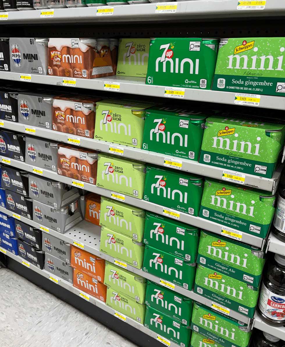 Paquet de six mini canettes de boissons gazeuses vari\u00e9es sur les tablettes du Dollarama.