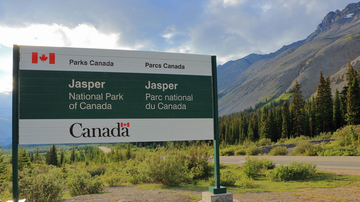 parks canada sign in front of a road and mountains at jasper national park
