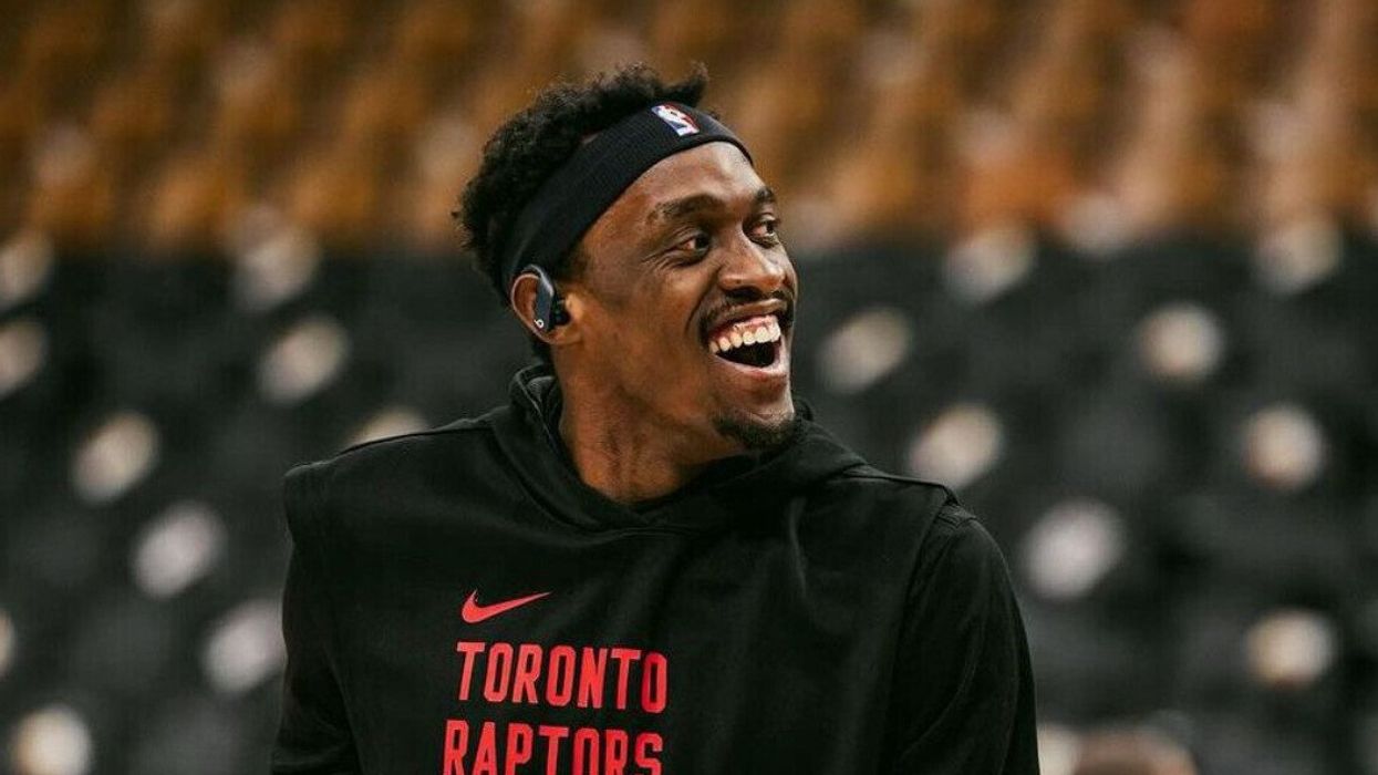 Pascal Siakam wearing a Toronto Raptors sweater and smiling to someone off camera.