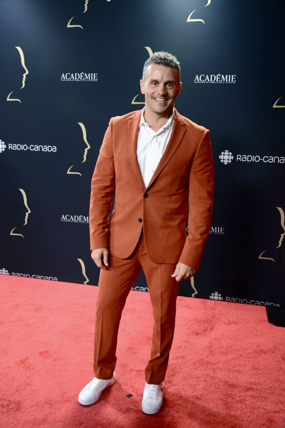 Patrice B\u00e9langer en complet orang\u00e9 \u200bsur le tapis rouge des Prix G\u00e9meaux.