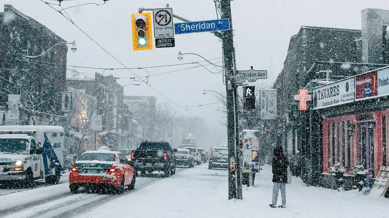 people and cars on a toronto street during a snowstorm