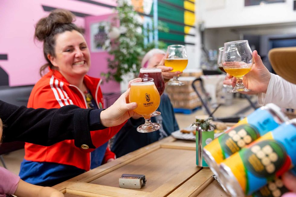 People cheers glasses of beer over a table at Tin Whistle Brewing Co.