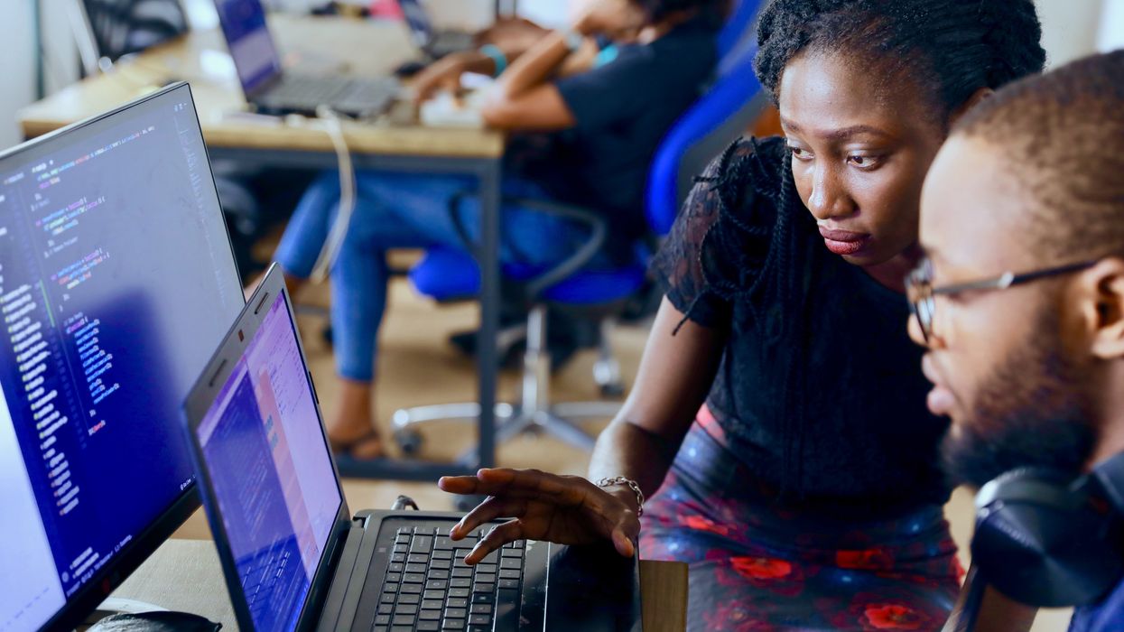 People coding on computers in an office.