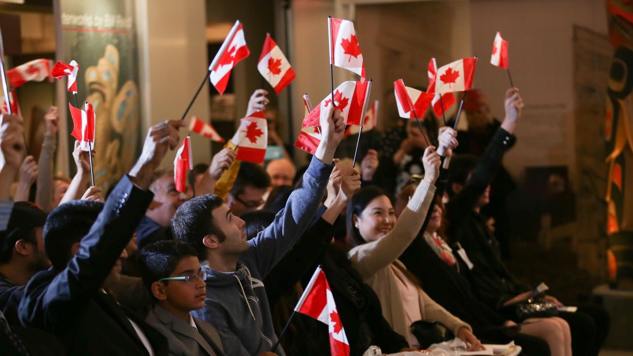 People holding up Canadian flags at a citizenship ceremony.