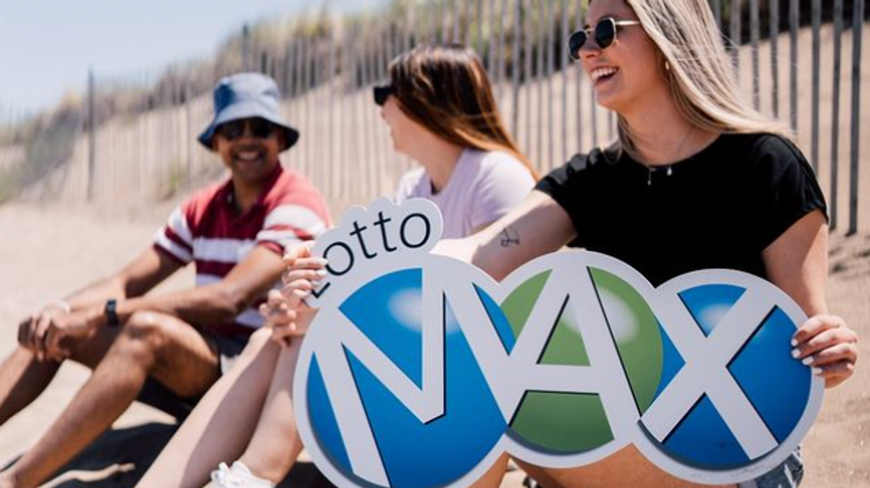 People on a beach holding a Lotto Max sign.