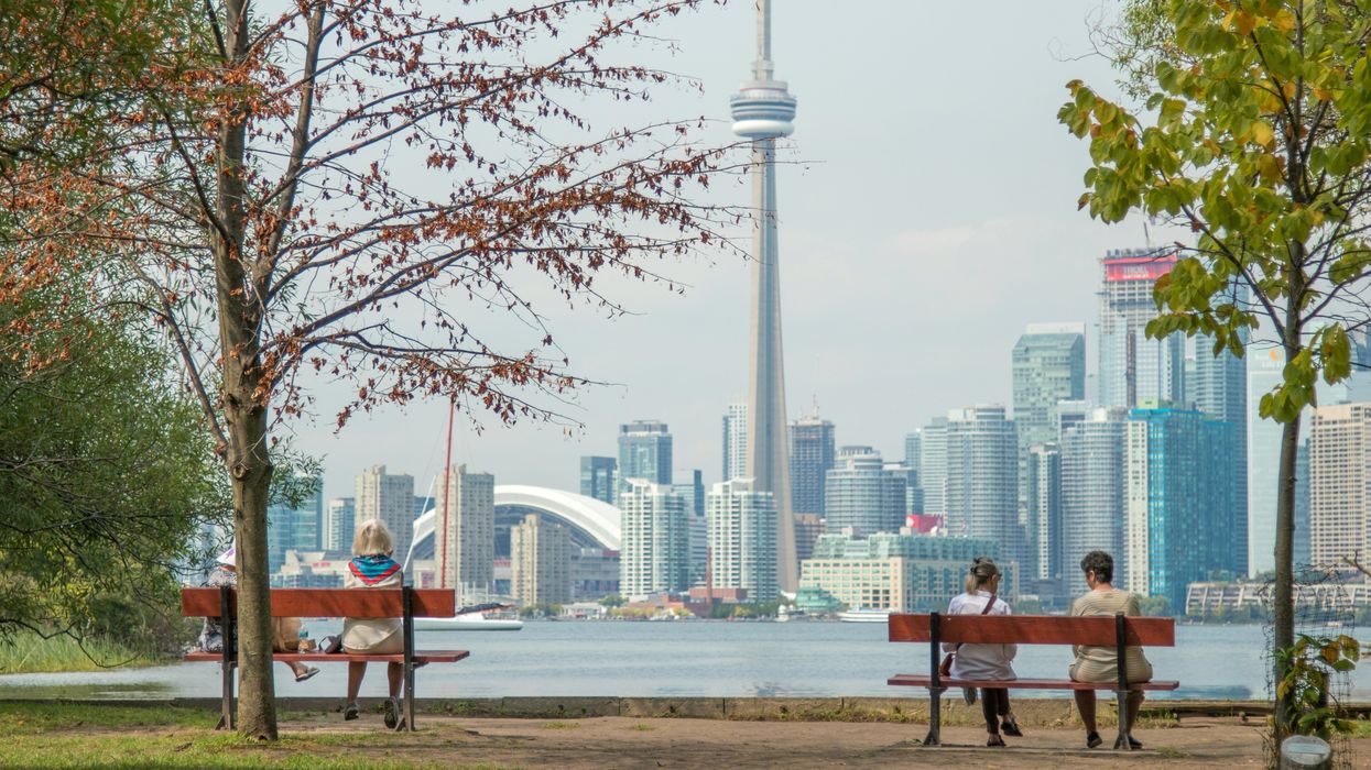 people on benches at the toronto islands looking at the toronto skyline with the cn tower