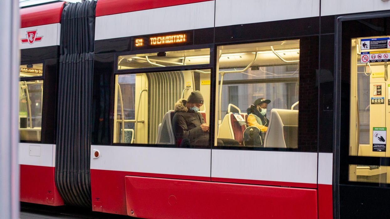 People ride a streetcar while wearing face masks.