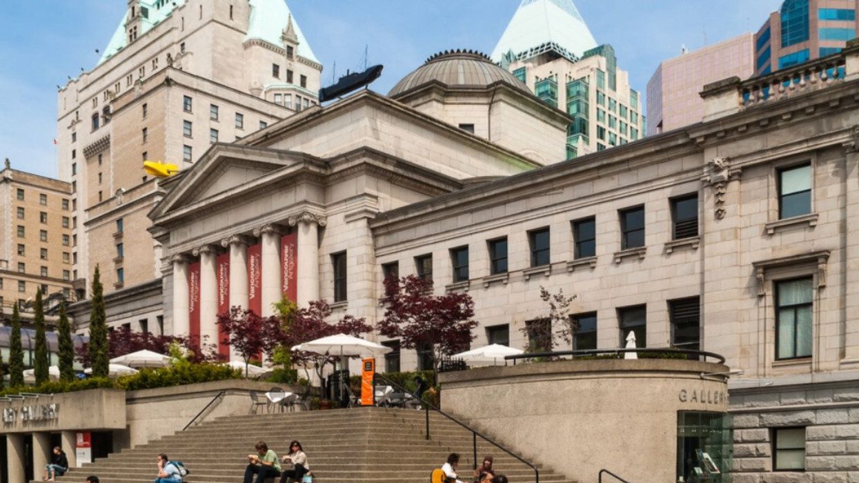 People sitting on the steps outside of the Vancouver Art Gallery building.