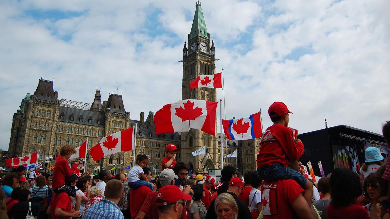 People stood outside Parliament Hill in Ottawa waving Canadian flags.