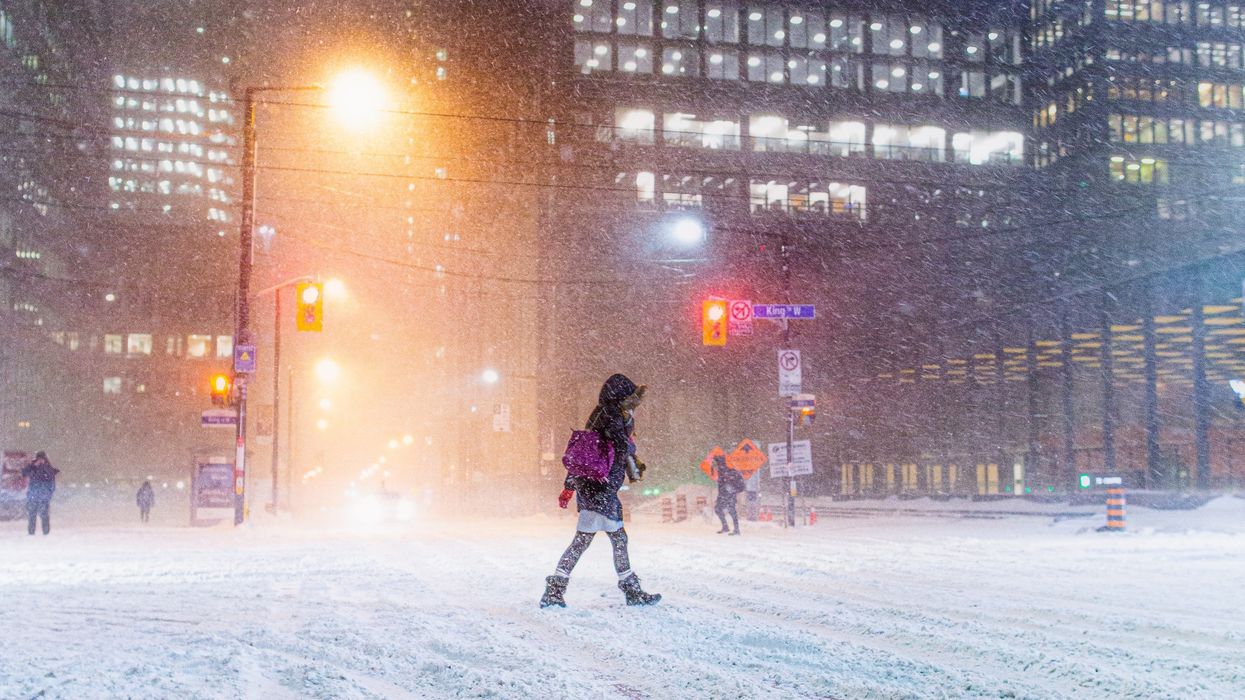 people walking across a snow-covered downtown street during a snowstorm in toronto