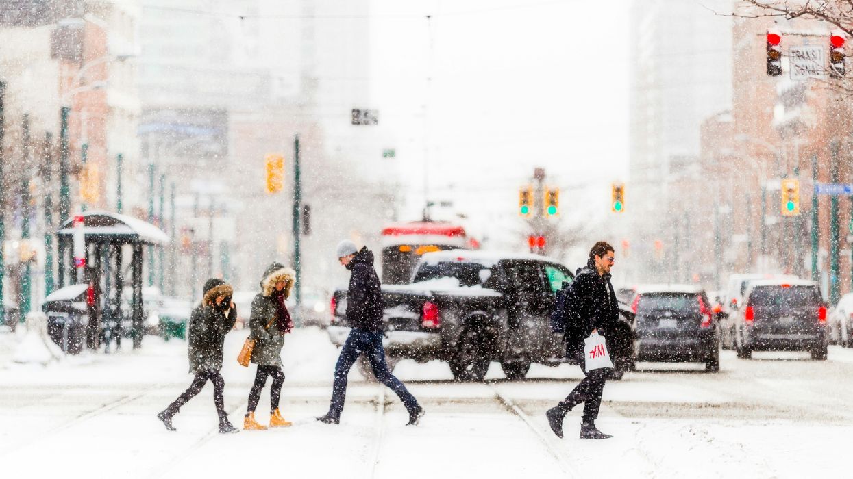 people walking across a toronto street in front of cars as it snows