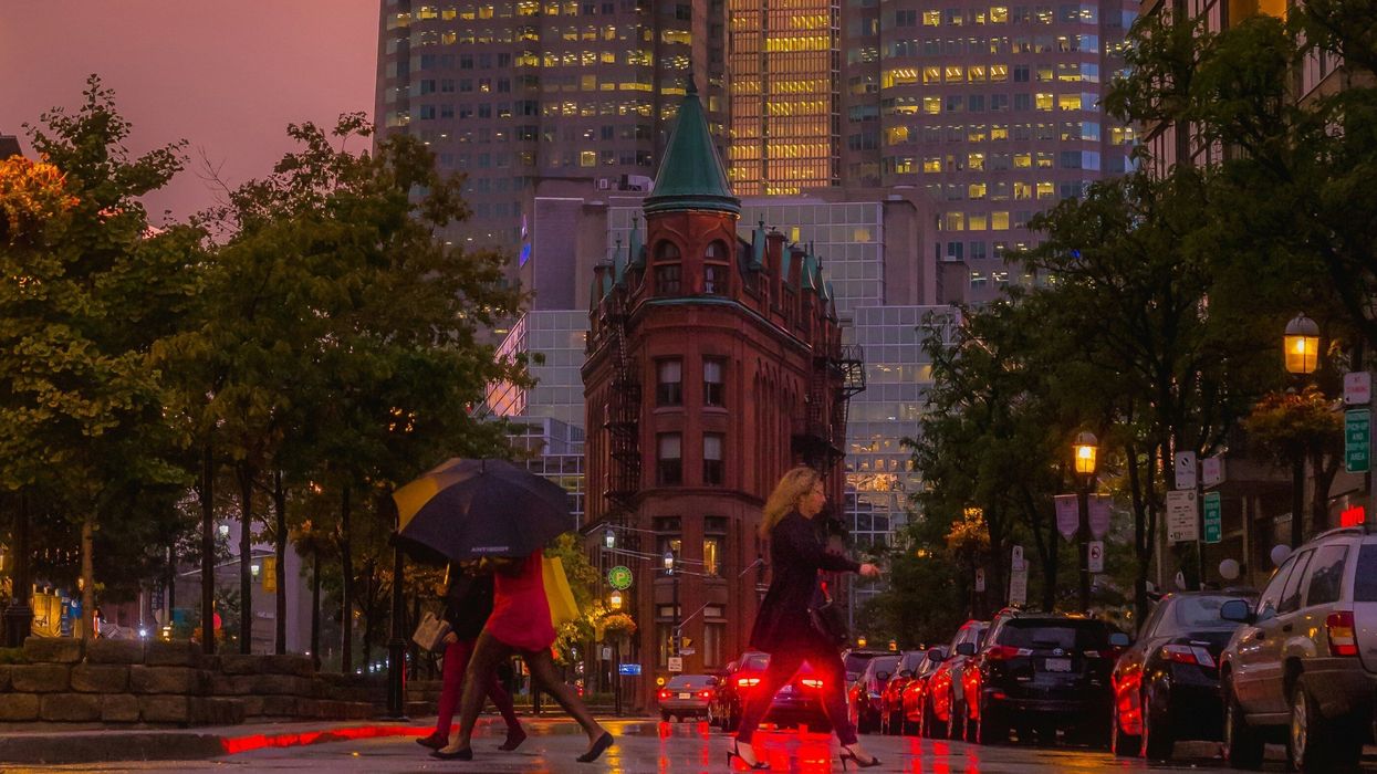 people walking on a rainy night in toronto with the flatiron building in the background.