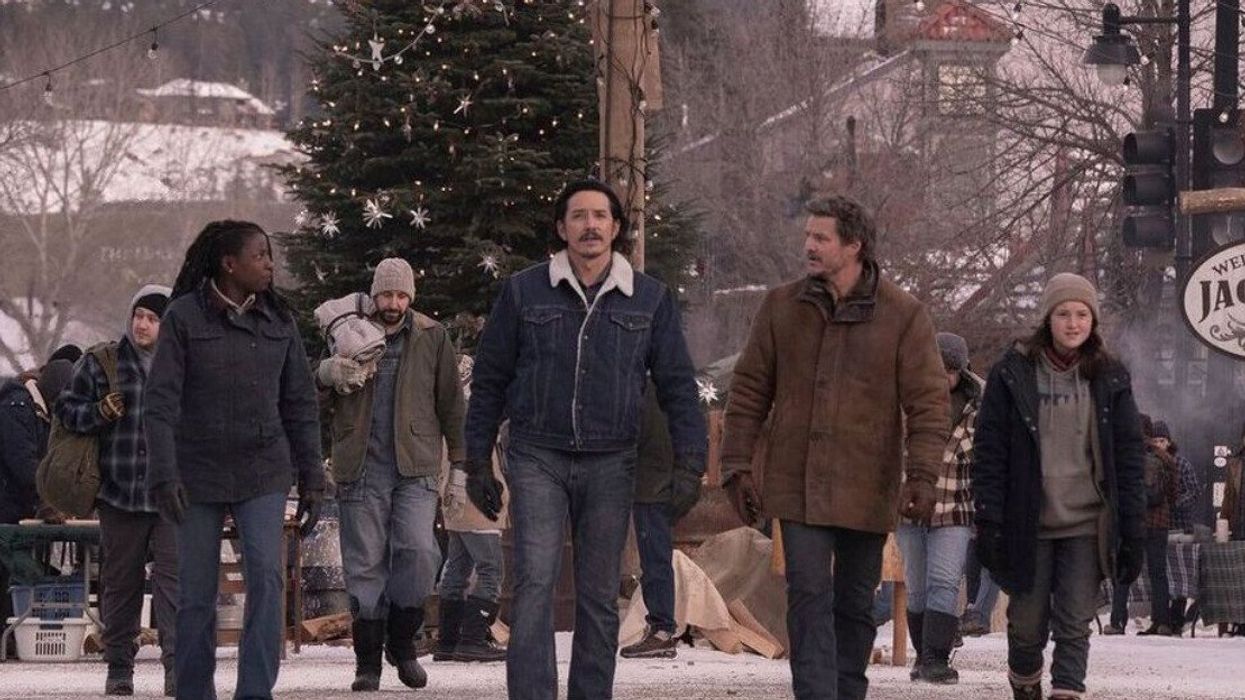 People walking on a street with a Christmas tree behind them and a sign that says "Welcome to Jackson."