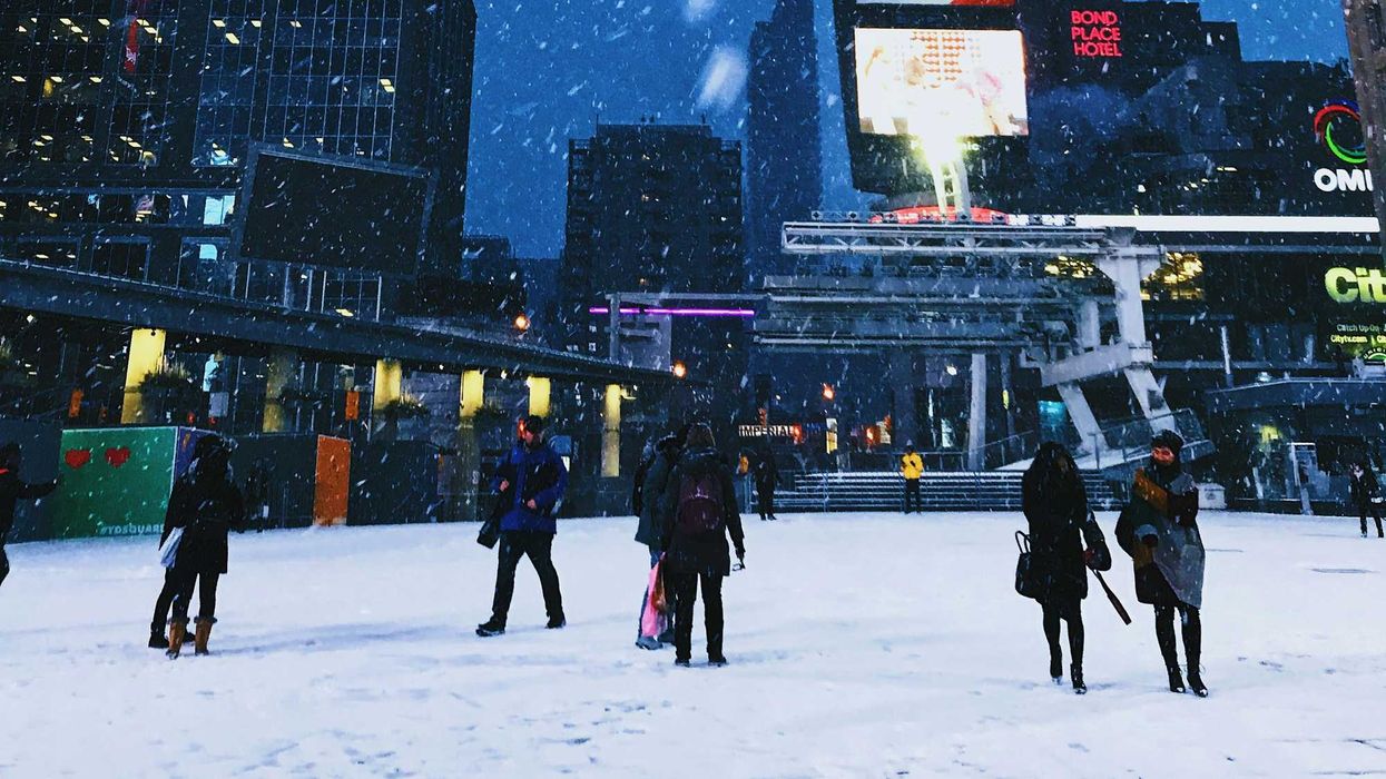 people walking through sankofa square in toronto during snowstorm