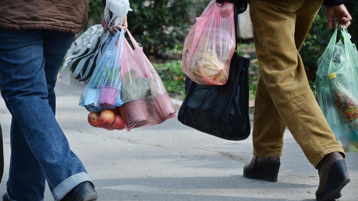 People walking while carrying multiple single-use plastic bags.