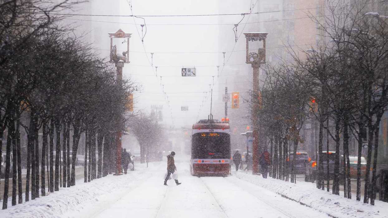 person crossing toronto street with ttc streetcar during snowstorm