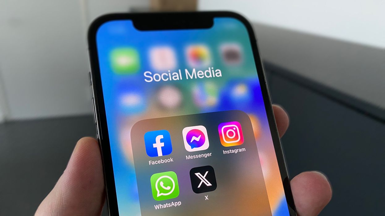 person holding a black iphone with a facebook app downloaded on it