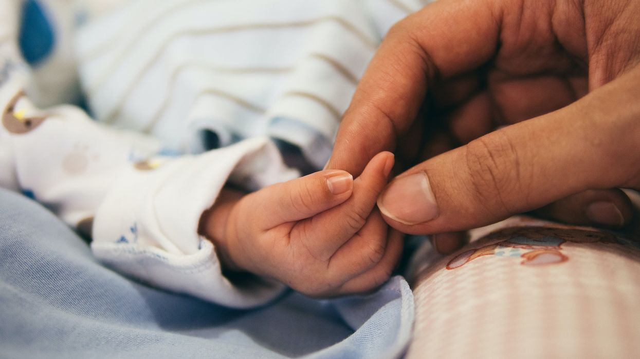 Person holding a newborn baby's hand.