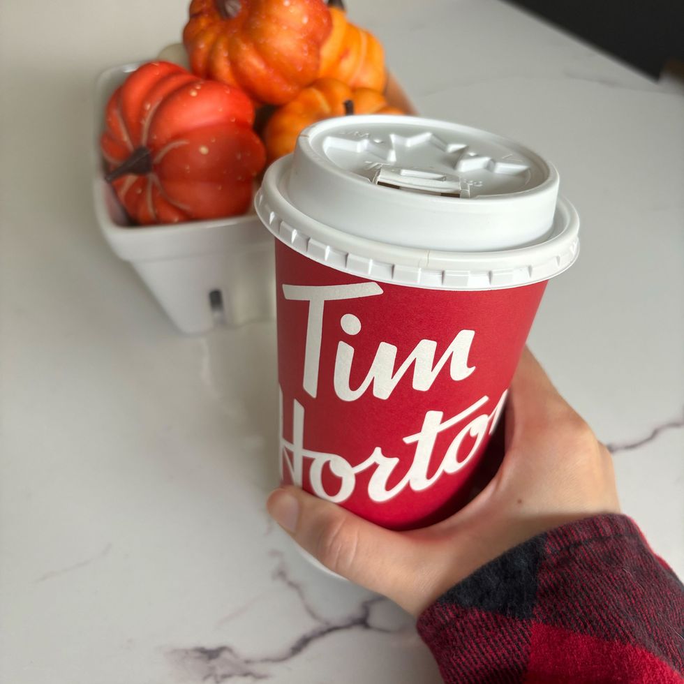 person holding a tim hortons cup filled with a psl