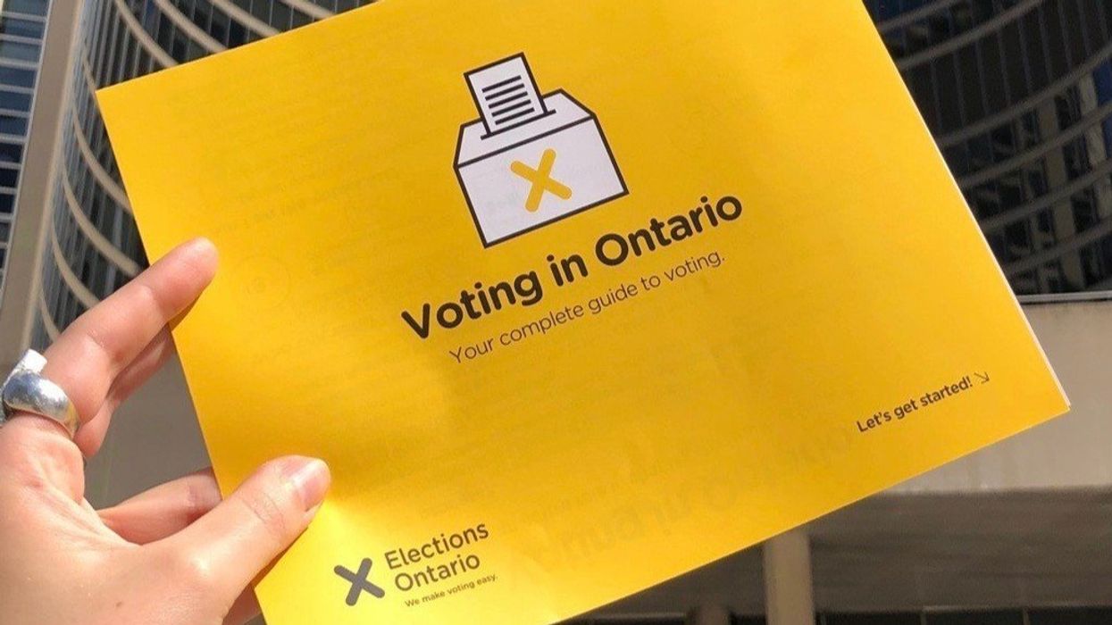person holding a yellow elections ontario guide on voting in ontario